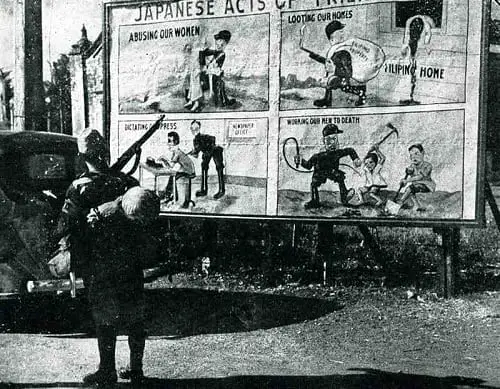 A Japanese soldier stand in front of US propaganda, in the Philippines